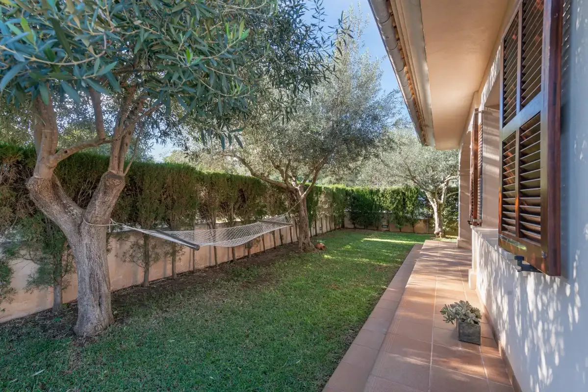 Un césped y un camino de baldosas bordean una casa con ventanas de contraventanas.