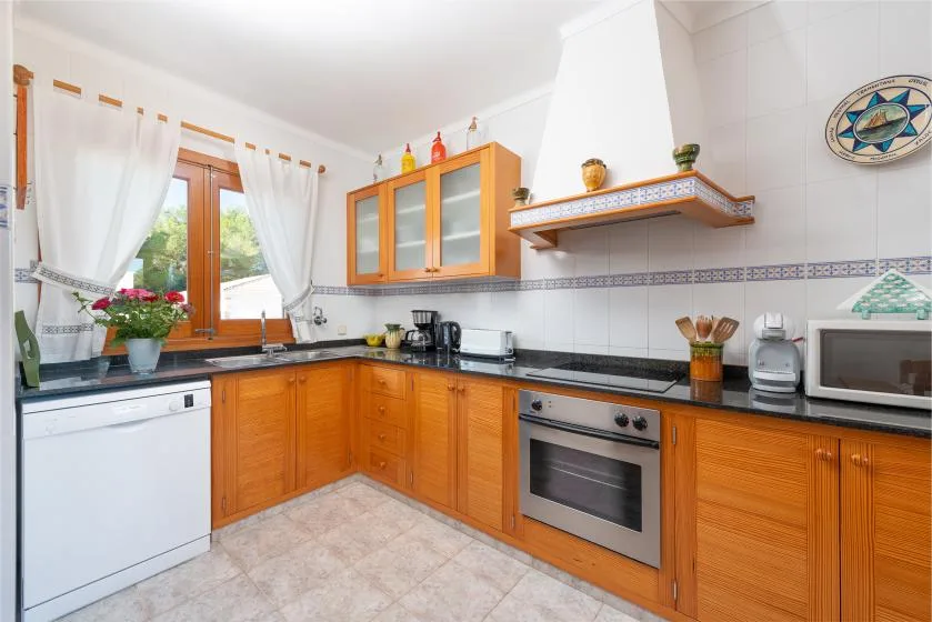 Una cocina luminosa con gabinetes de madera, azulejos y una ventana.