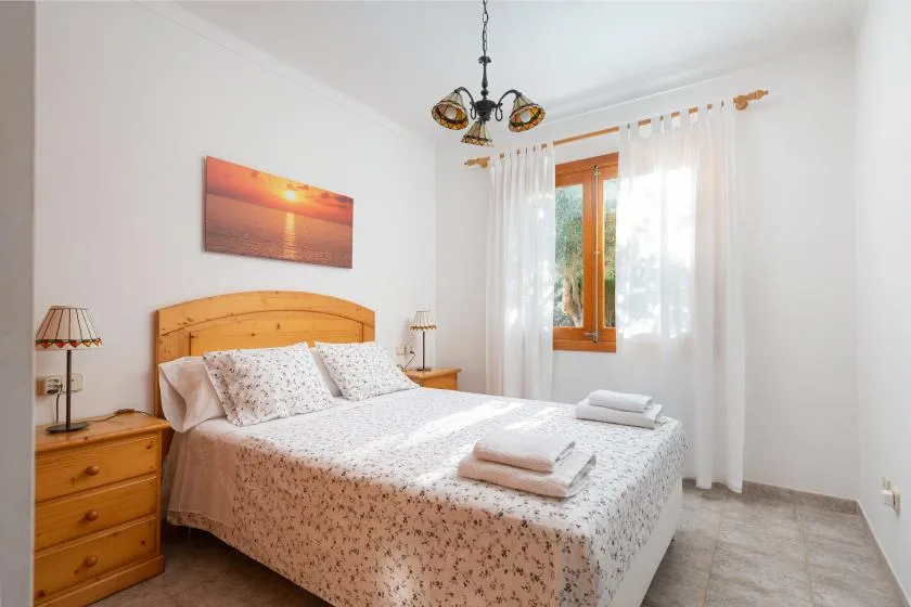 Un dormitorio luminoso con una cama hecha y una ventana soleada.