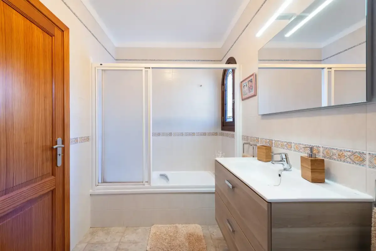 Un baño con bañera, mampara de ducha de vidrio y mueble de lavabo.