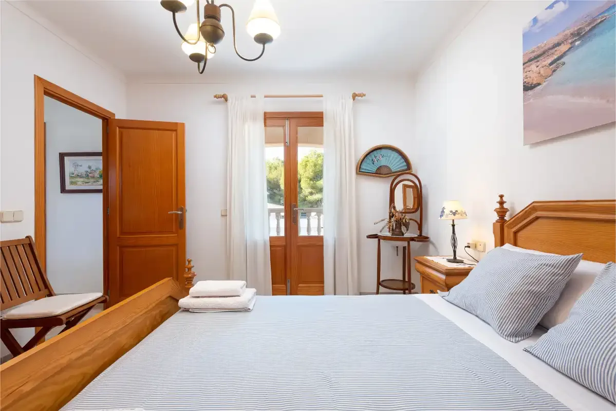 Un dormitorio luminoso con una cama grande y una puerta de madera.
