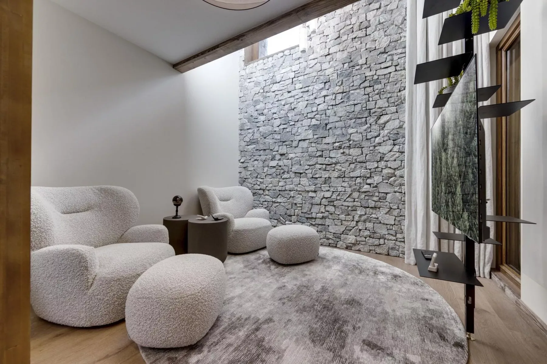 Una zona de estar moderna con asientos mullidos junto a una pared de piedra texturizada.