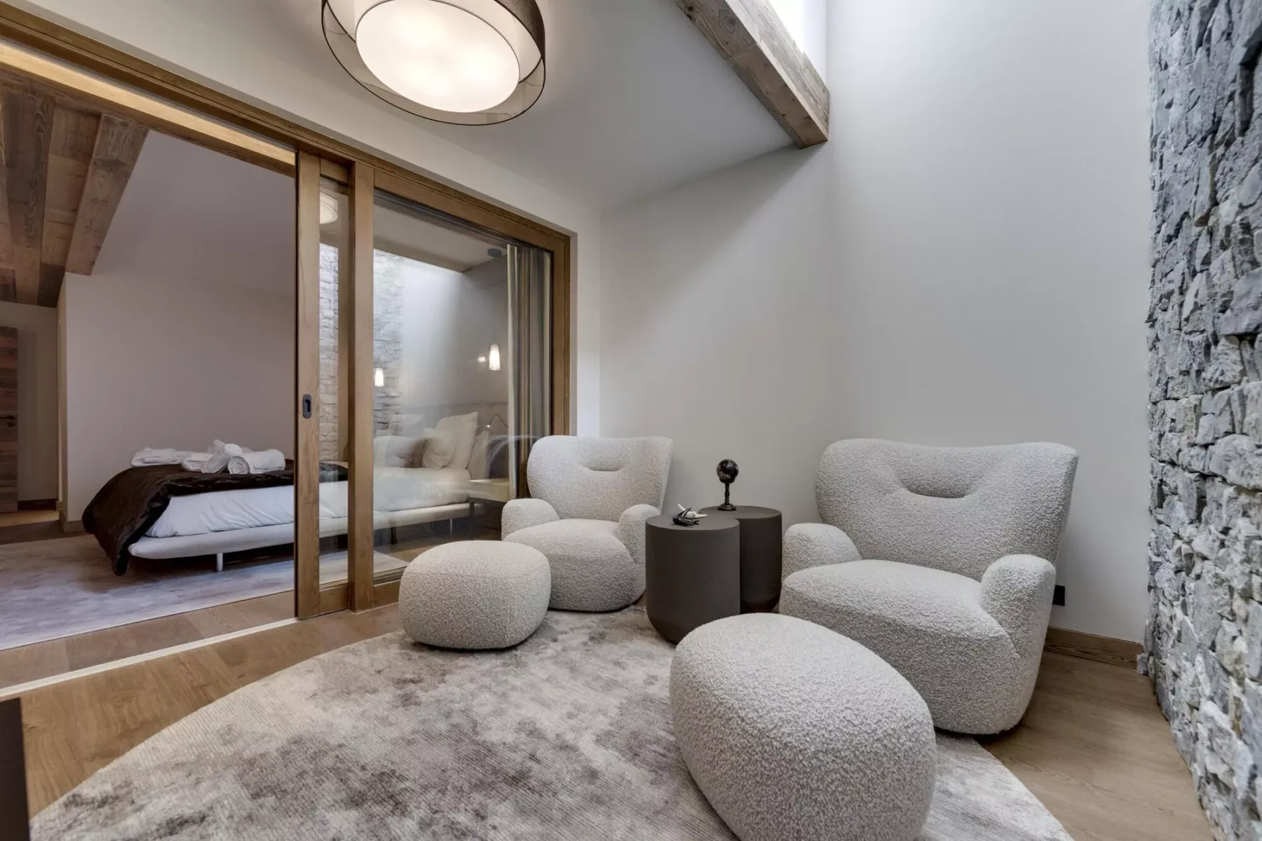 Una zona de estar con asientos acolchados y un panel de vidrio junto a un dormitorio.