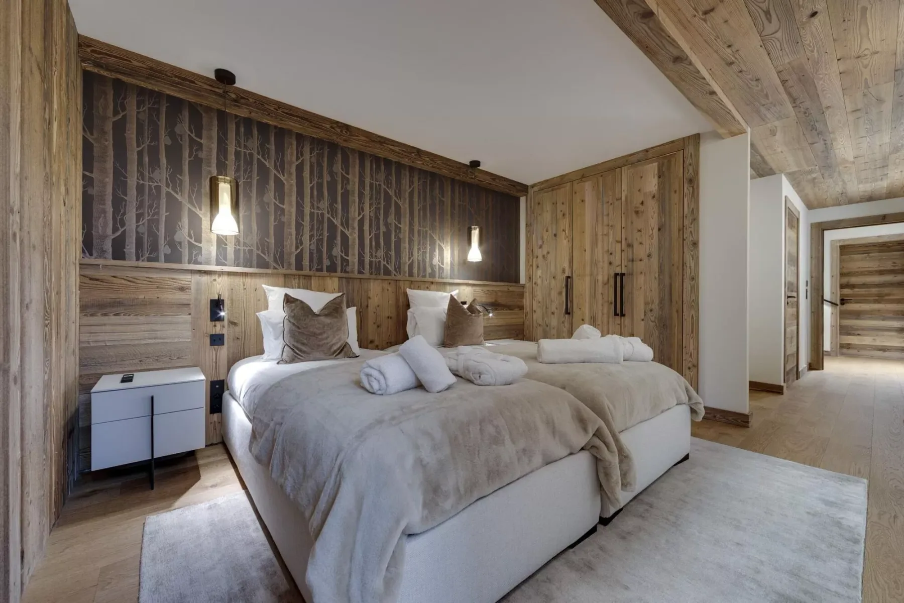 Un dormitorio con dos camas, mesillas y paredes revestidas de madera.