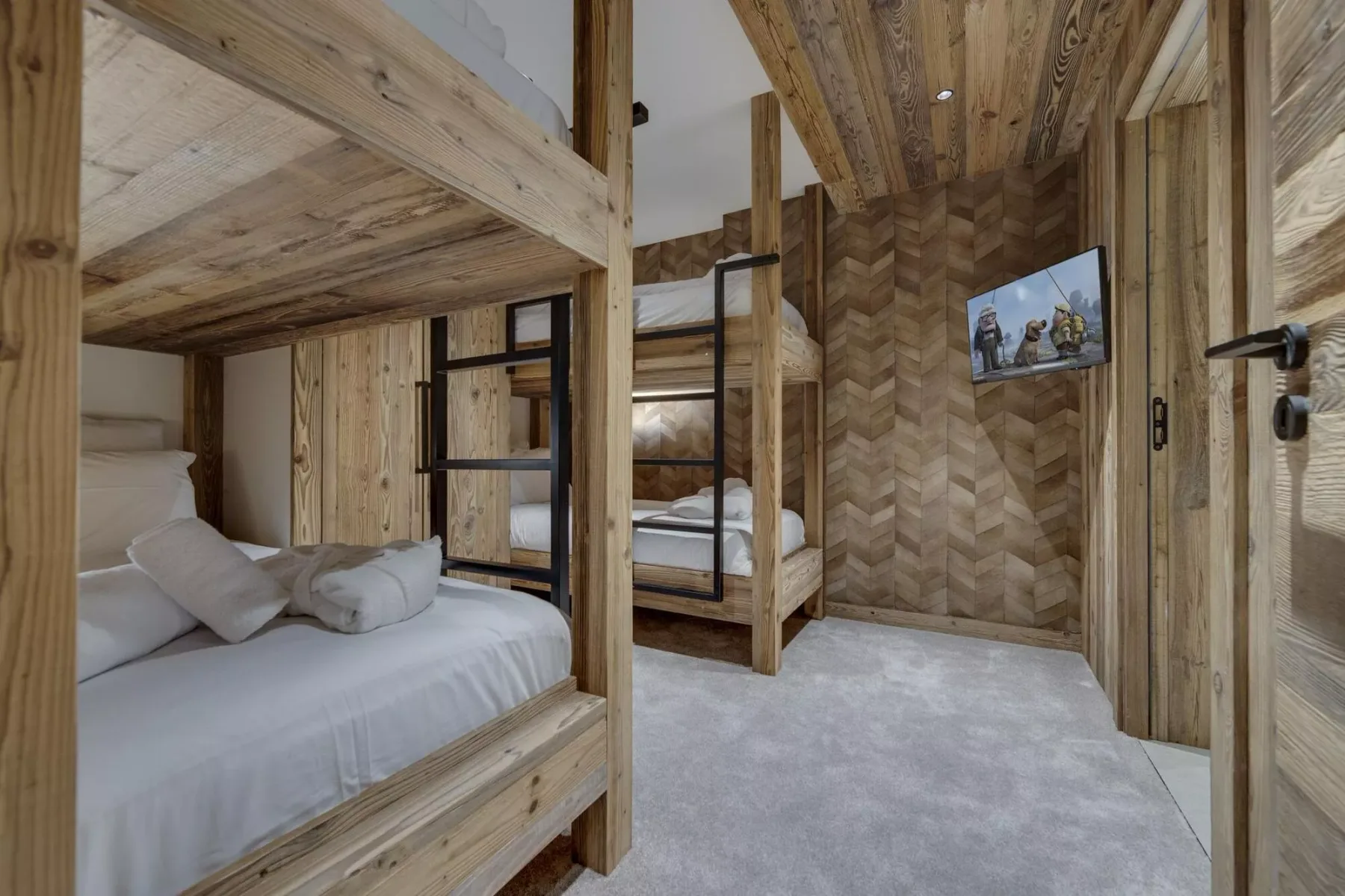 Un dormitorio revestido de madera con literas y un televisor en la pared.
