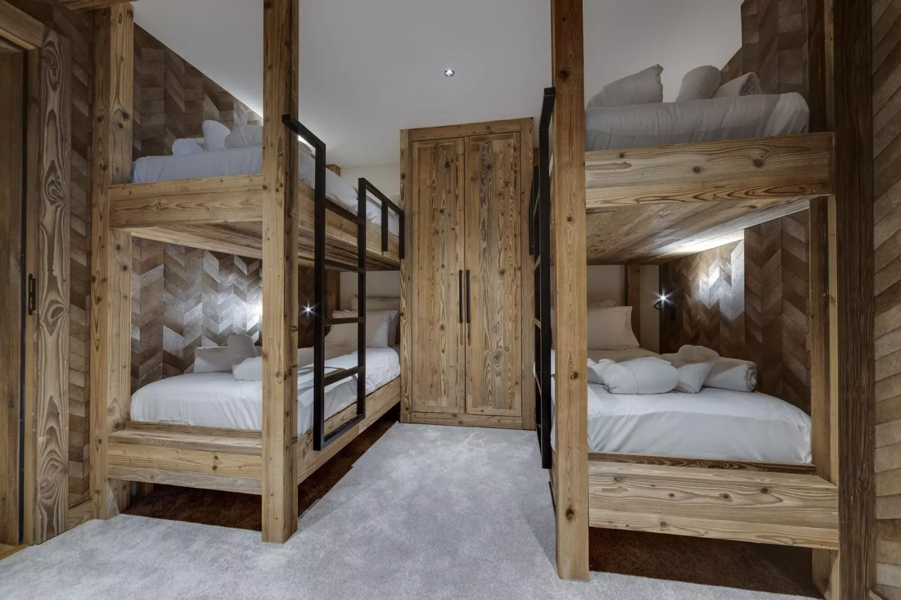 Un dormitorio con literas de madera, paredes revestidas y un pasillo central.