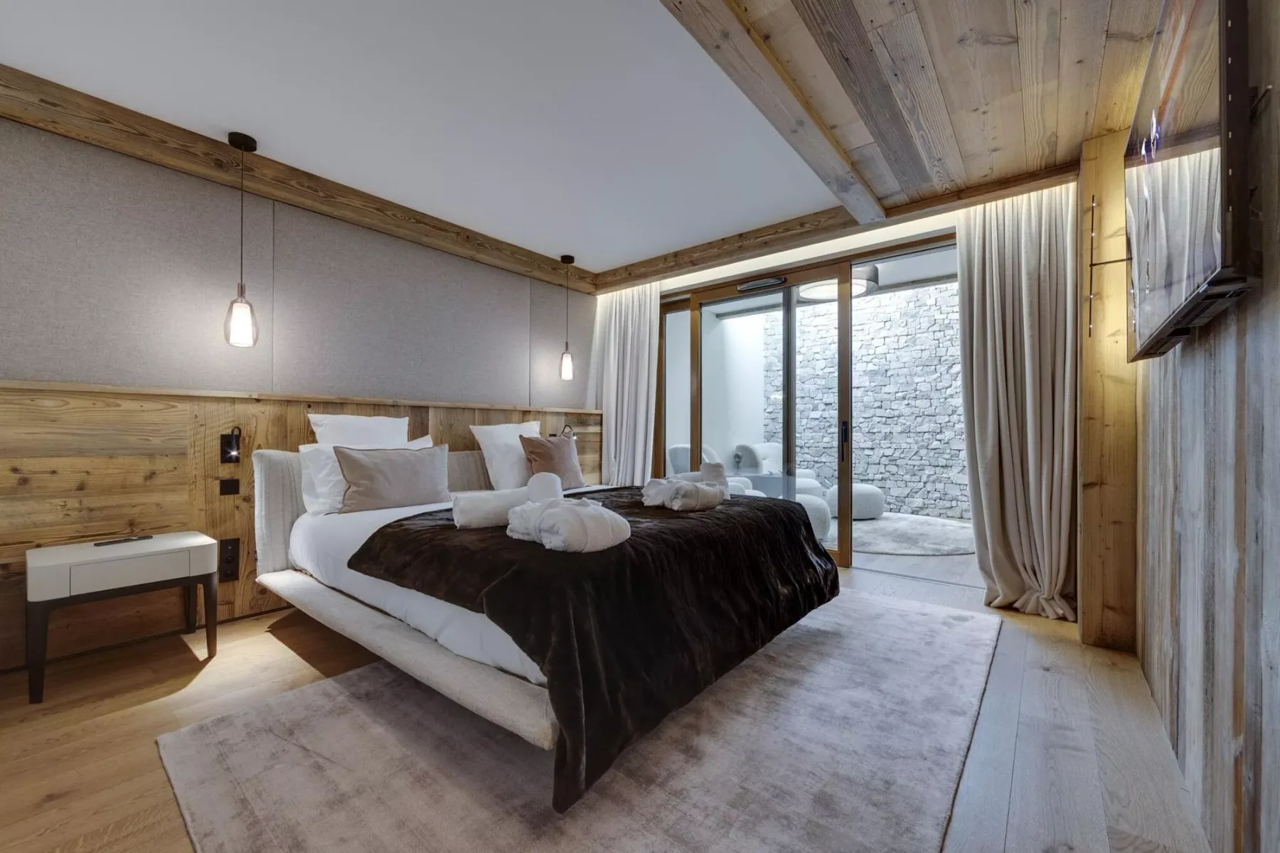 Un dormitorio con una cama grande, paredes revestidas de madera y puertas corredizas de vidrio.
