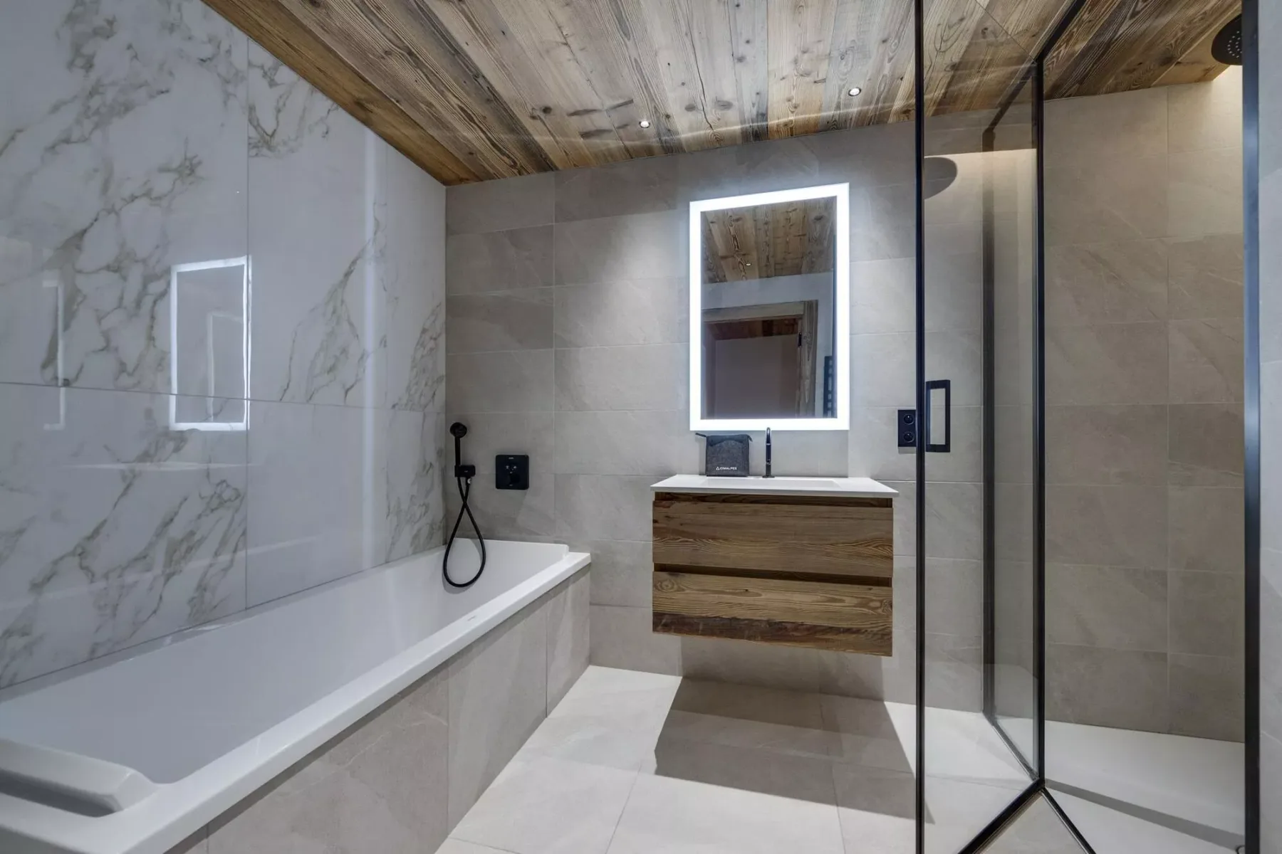 Un baño moderno con bañera, ducha y espejo iluminado.