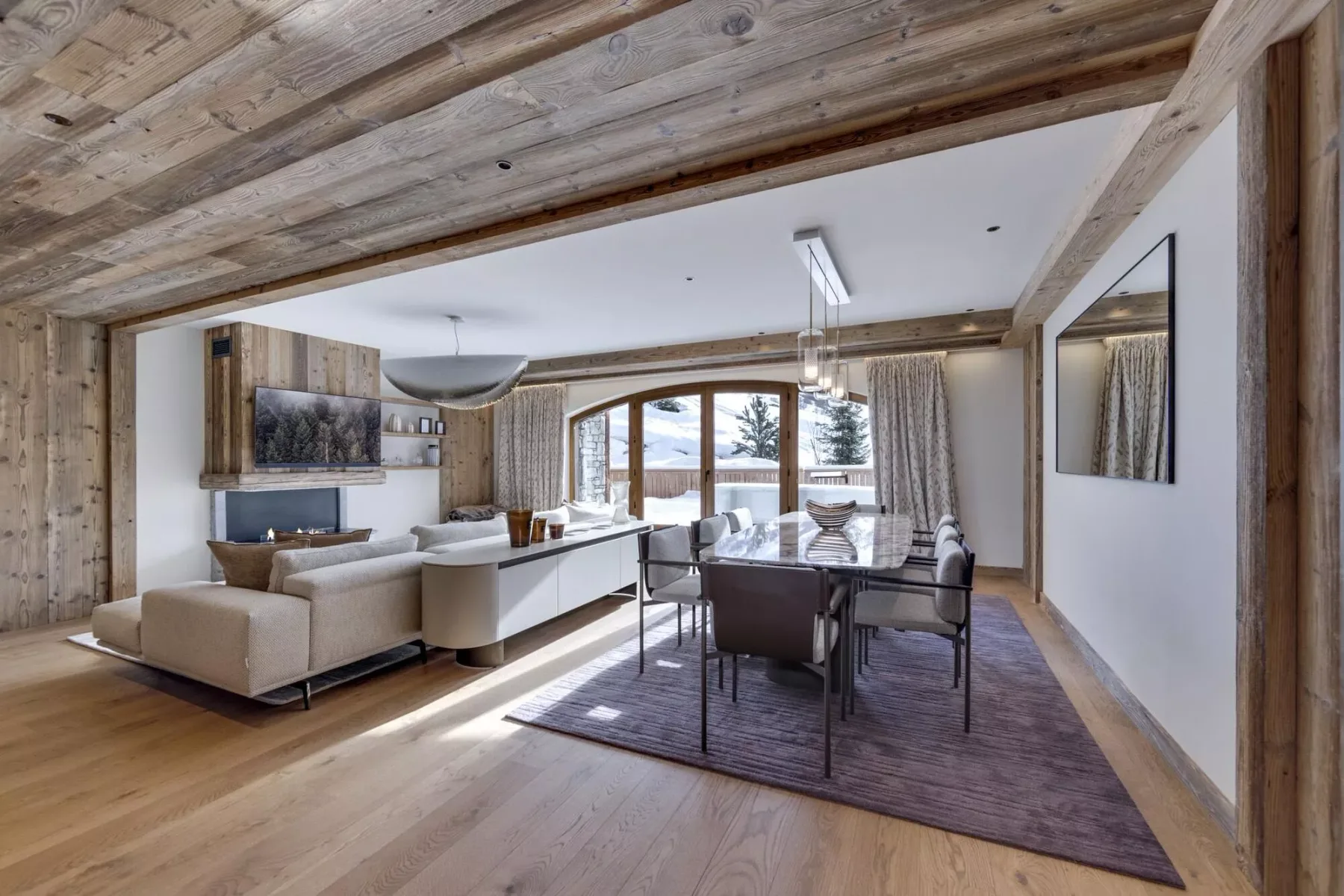 Una sala de estar y comedor diáfana con asientos junto a grandes ventanas.