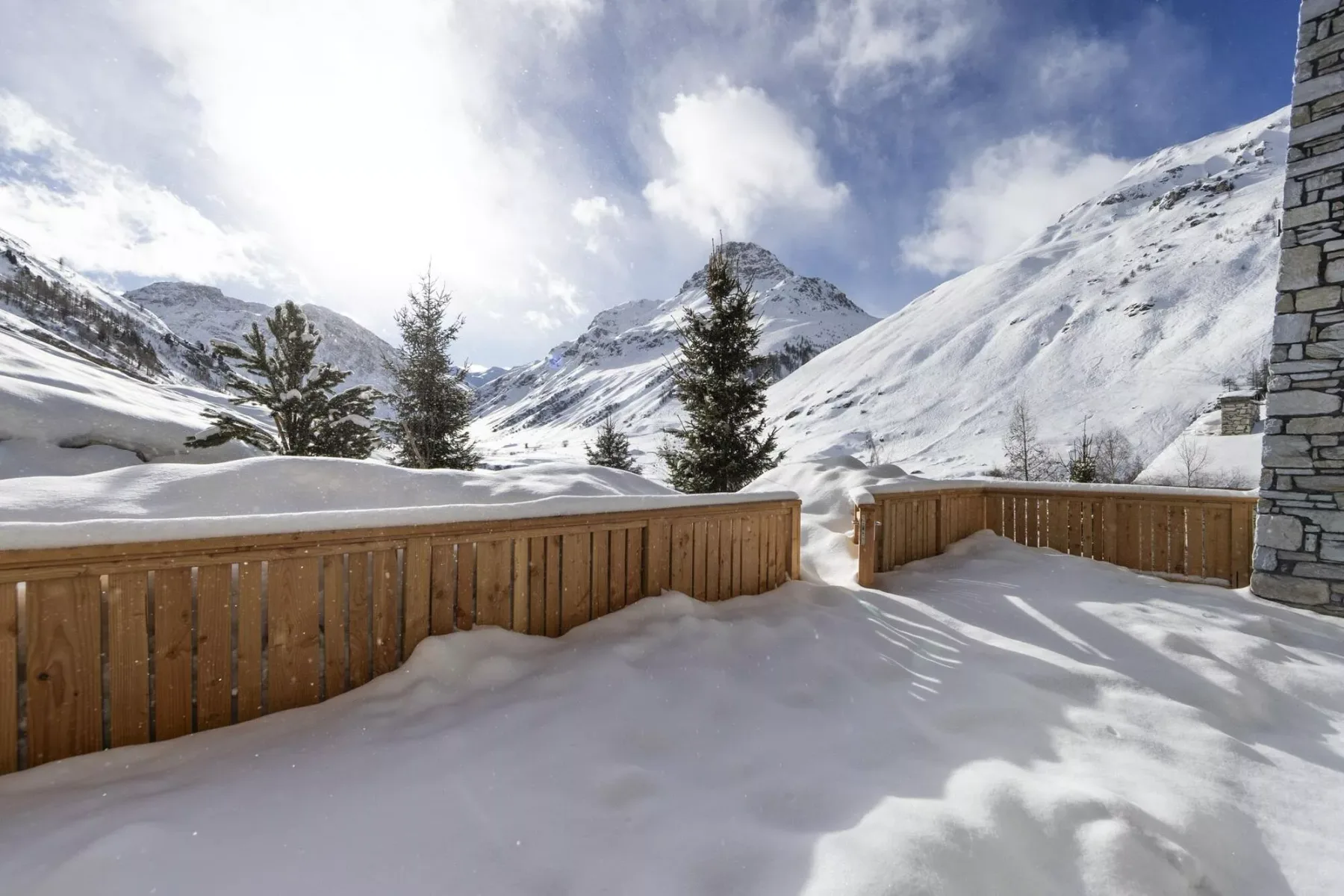 Una terraza exterior cubierta de nieve ofrece vistas a las cumbres y los árboles de hoja perenne.