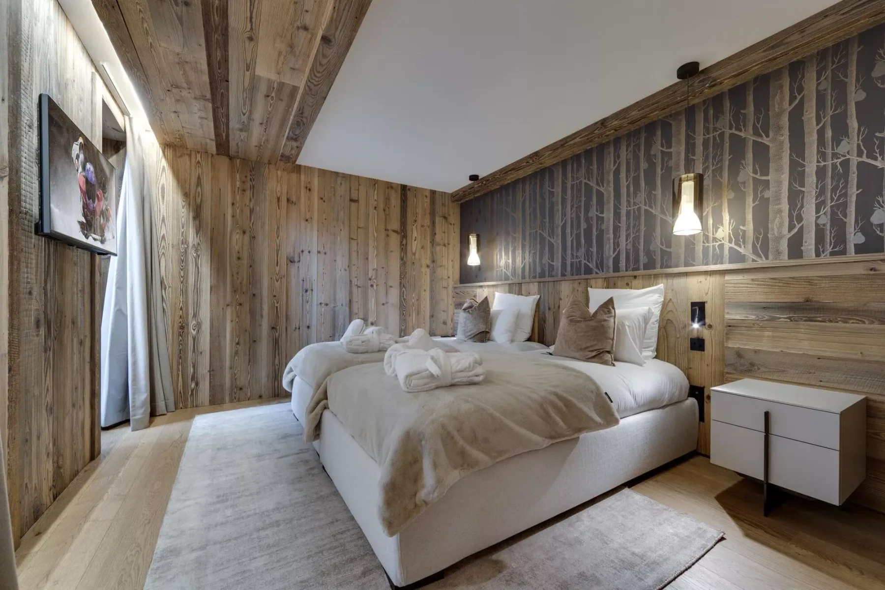 Un dormitorio con una cama grande, ropa de cama neutra y paredes revestidas de madera.