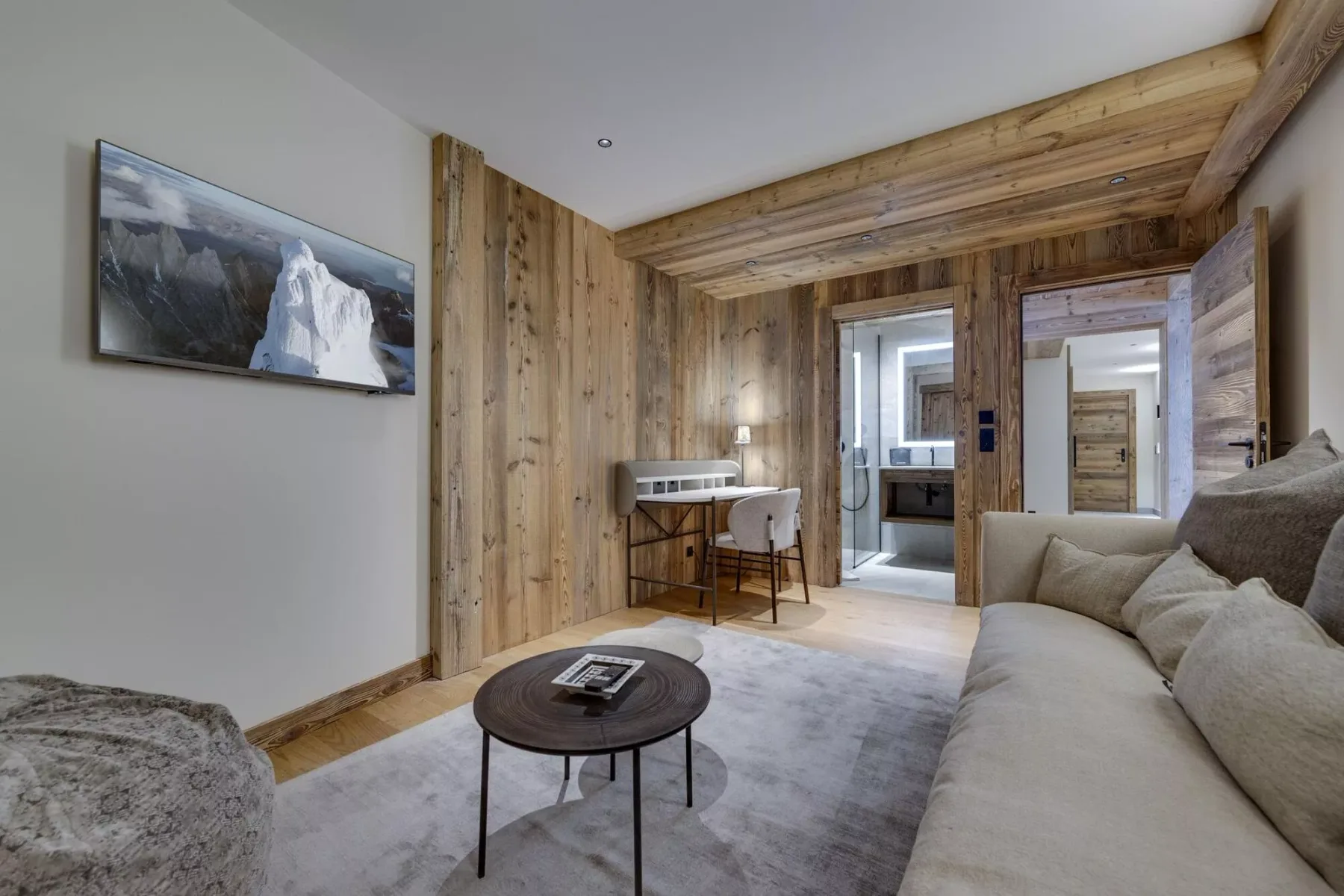 Sala de estar revestida de madera con asientos, una mesa de centro y un escritorio.