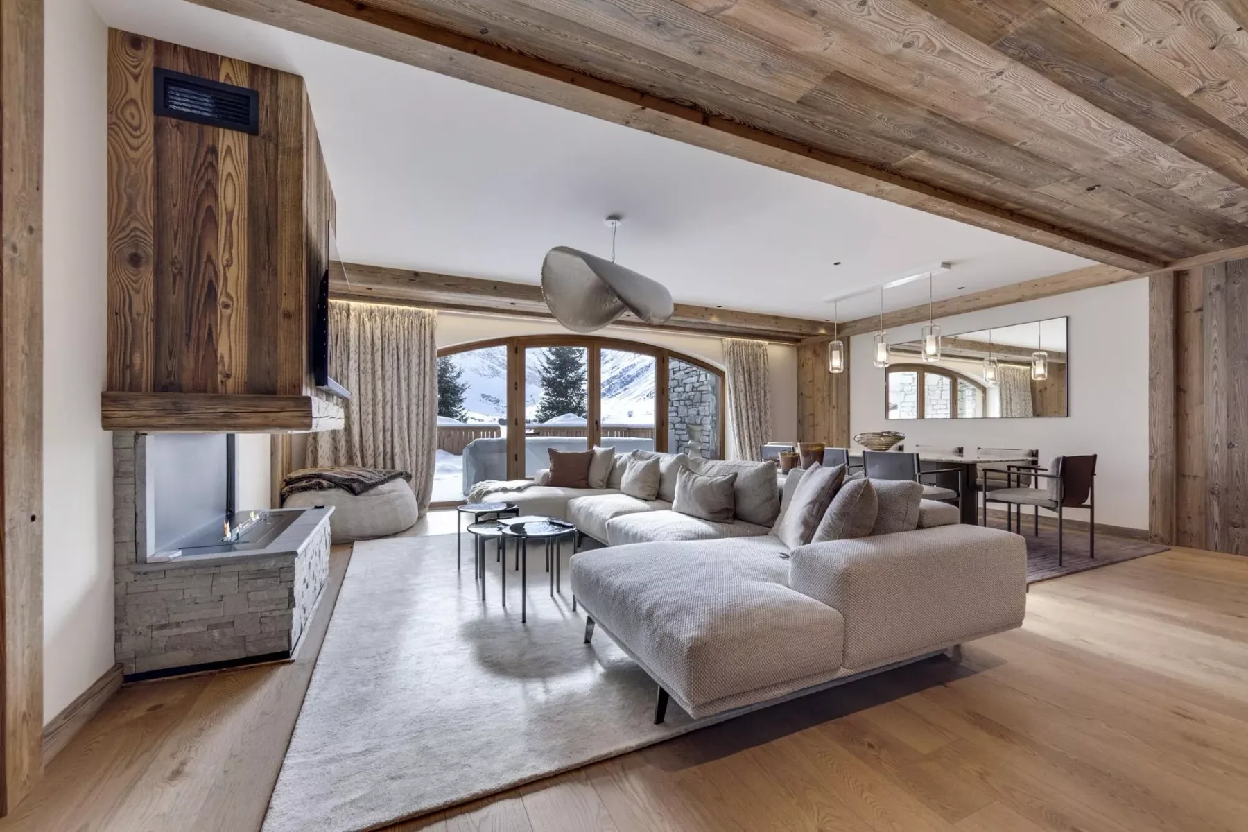 A spacious living room with sectional seating and large windows overlooking a snowy landscape.