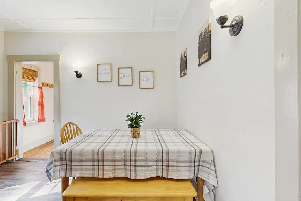 Comedor con una mesa cubierta con un mantel a cuadros y un banco de madera.