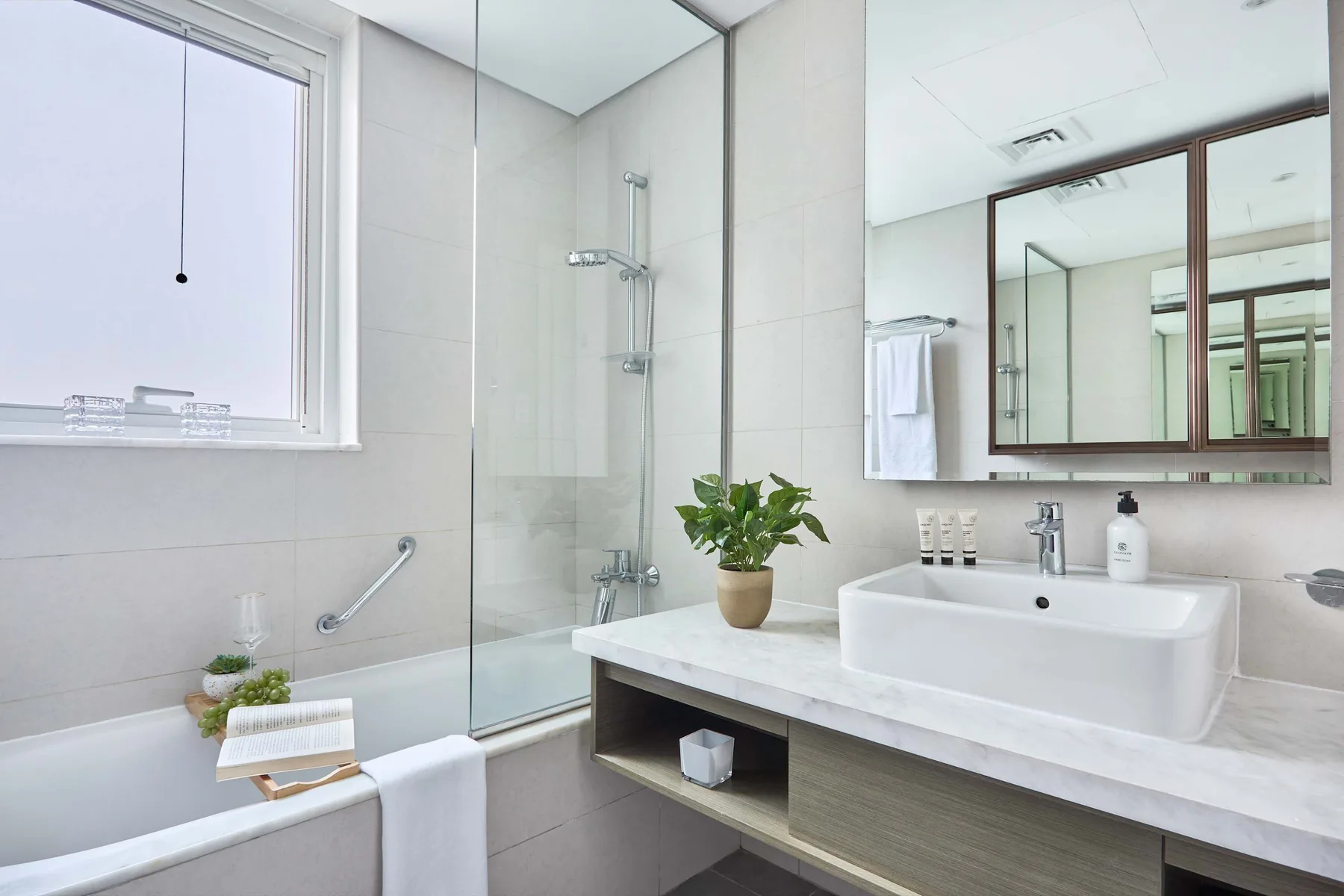 Un baño luminoso con bañera, ducha de vidrio y un amplio lavabo.