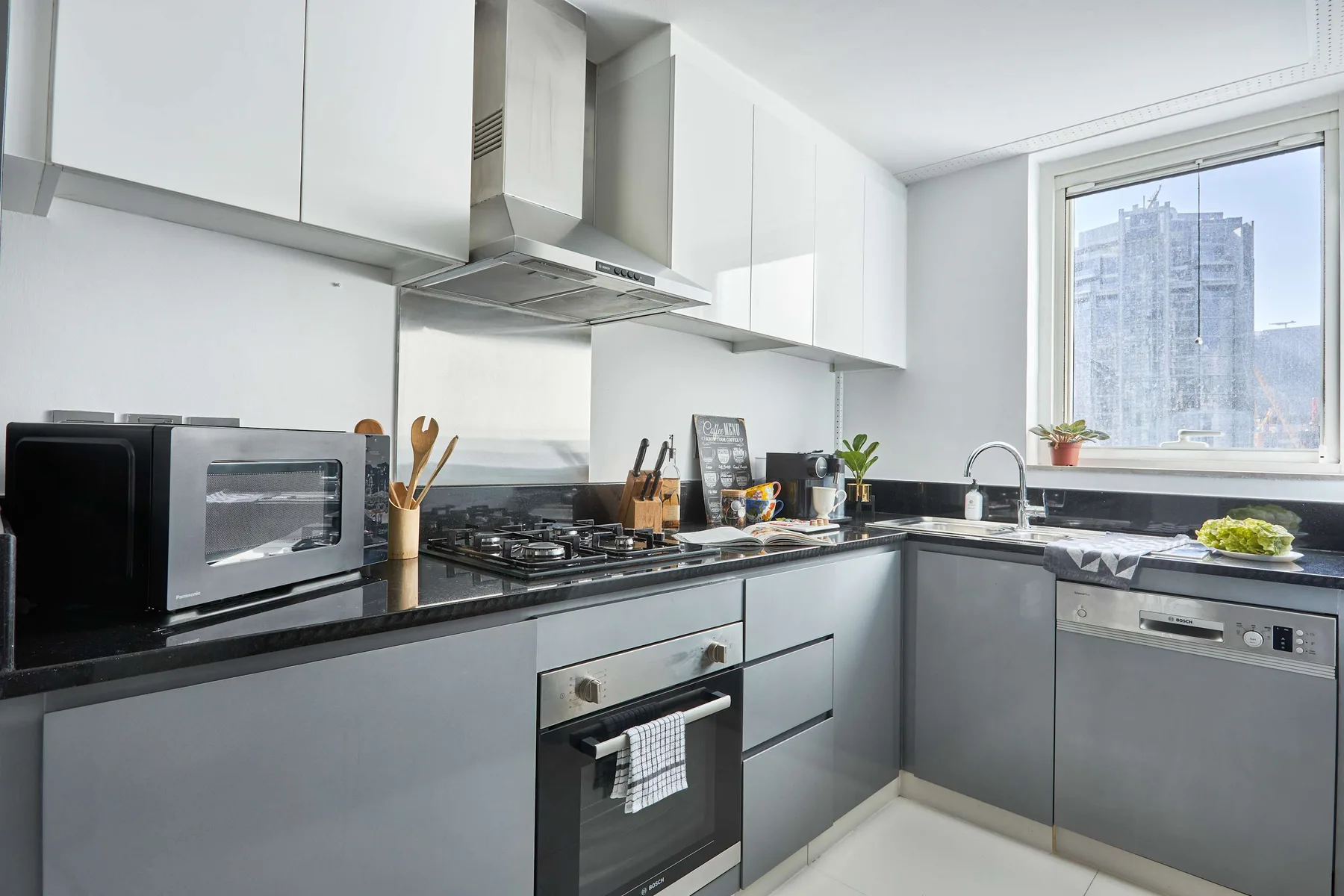 Una cocina moderna con armarios grises, encimeras oscuras y una ventana.