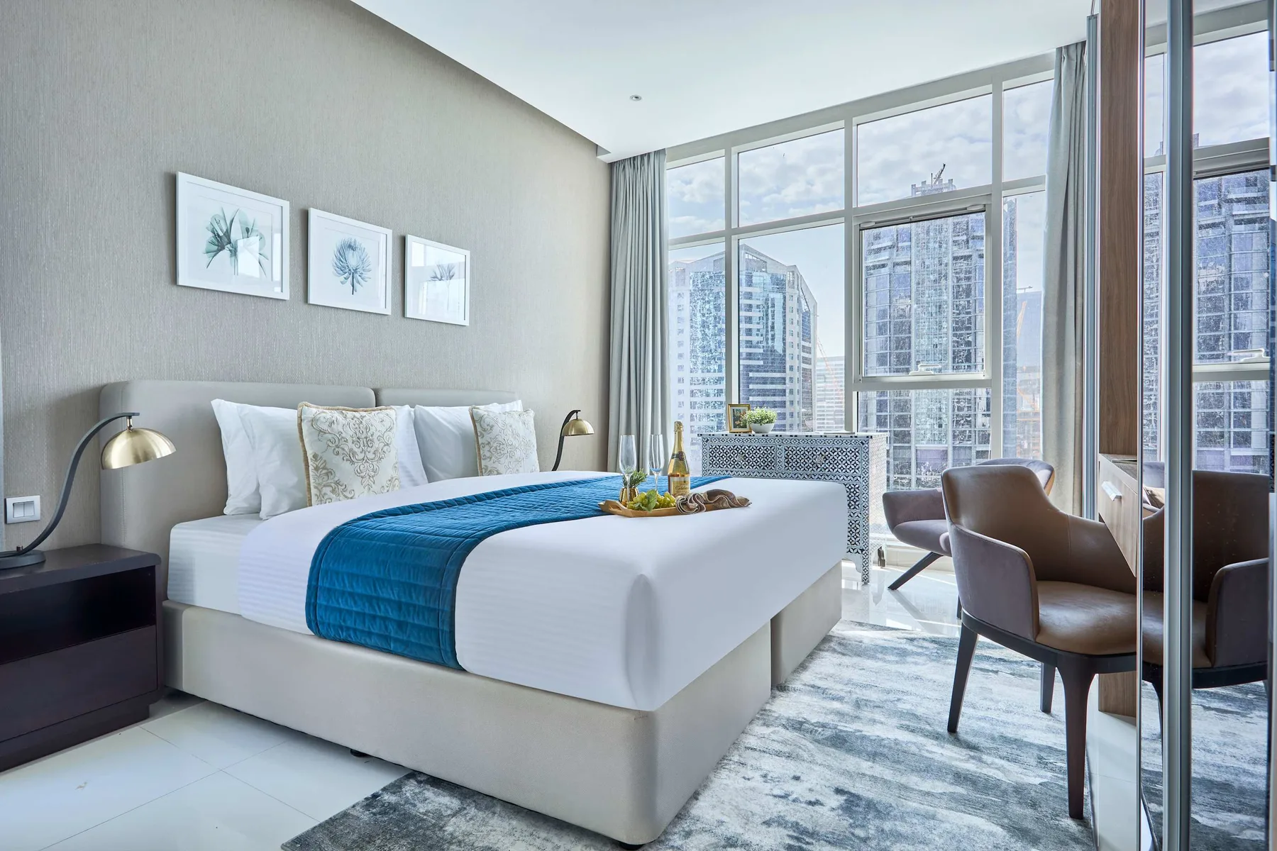 Un dormitorio luminoso con una cama bien tendida junto a ventanas de piso a techo.