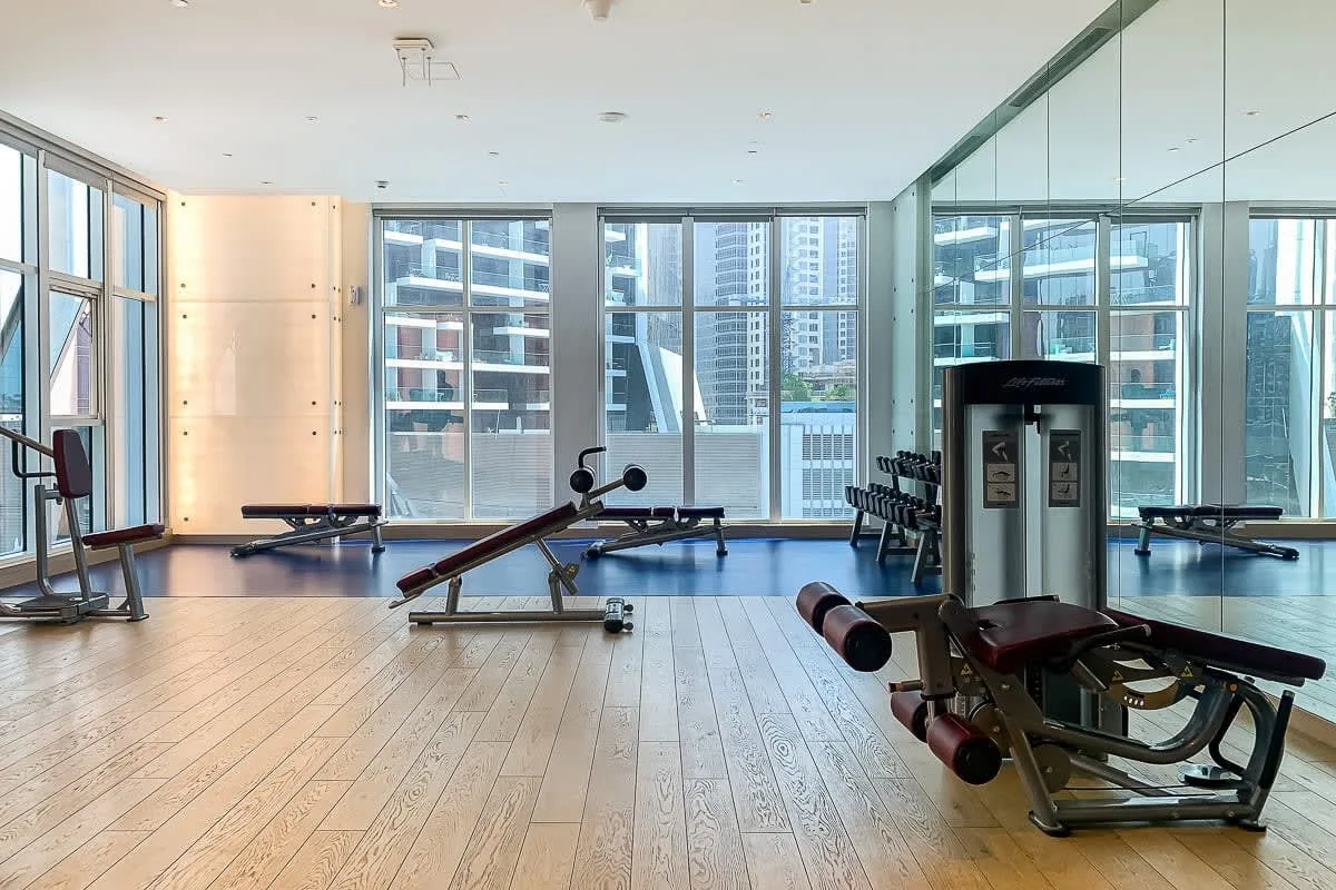 Una luminosa sala de ejercicios con equipo de entrenamiento y ventanales.