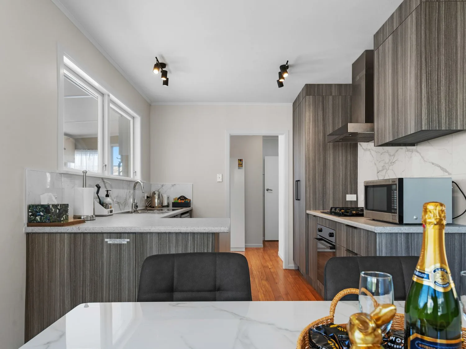 A modern kitchen with dark cabinets, a microwave, and a dining table.