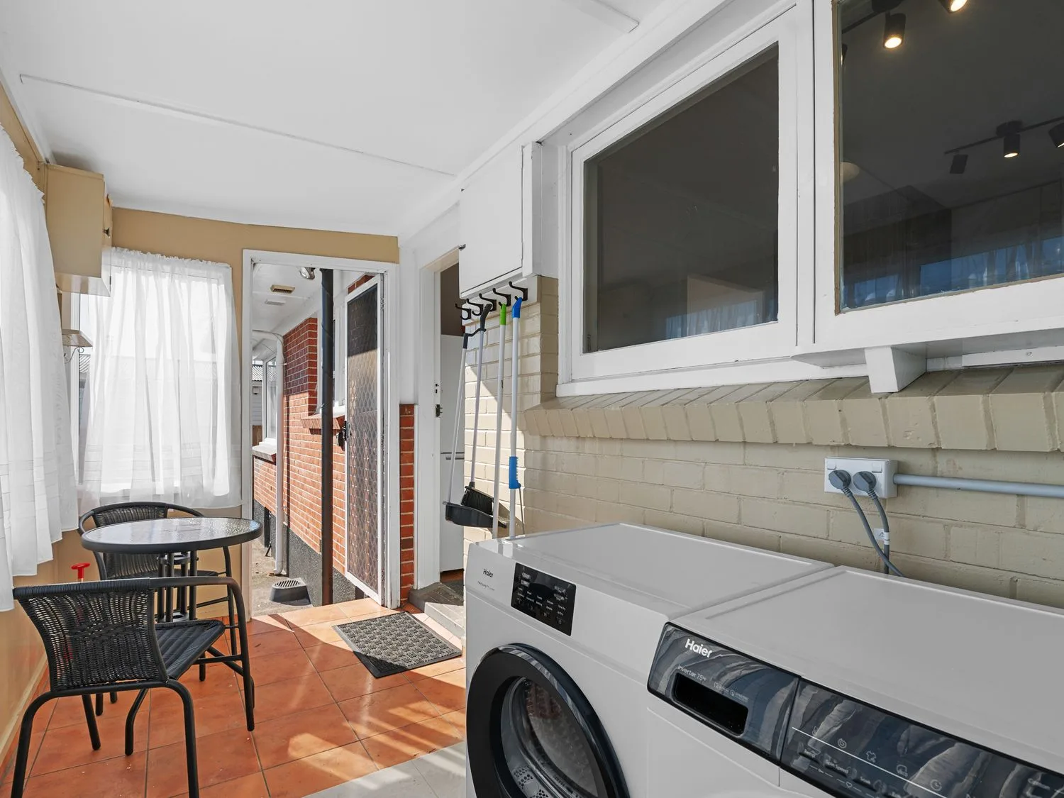 A laundry area with front-loading appliances and a small table with seating.