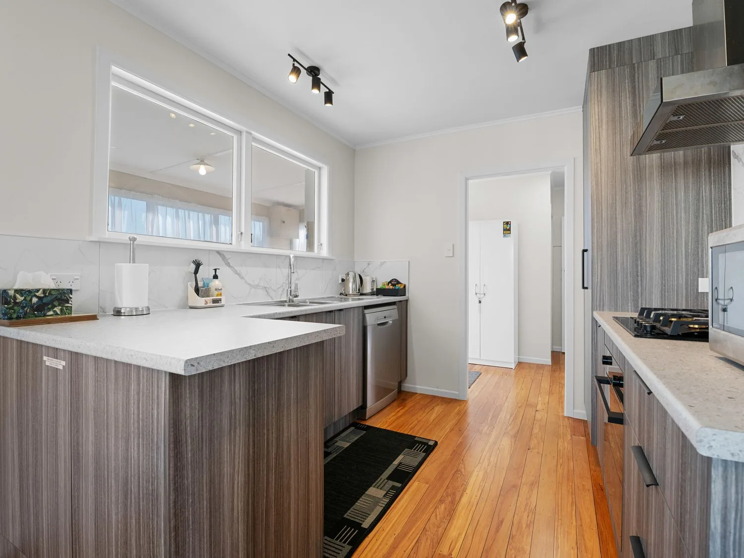 A kitchen with gray cabinets a dishwasher a sink and a stove at Owhata Retreat - Rotorua Holiday Home in Rotorua