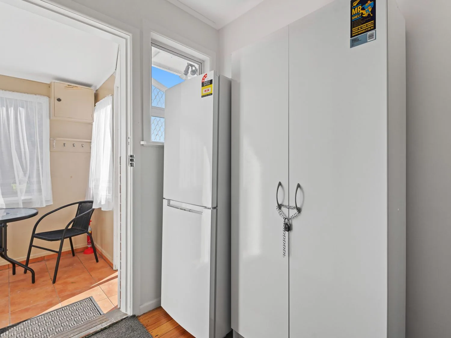 A kitchen with a white refrigerator beside a white cabinet secured with a chain.