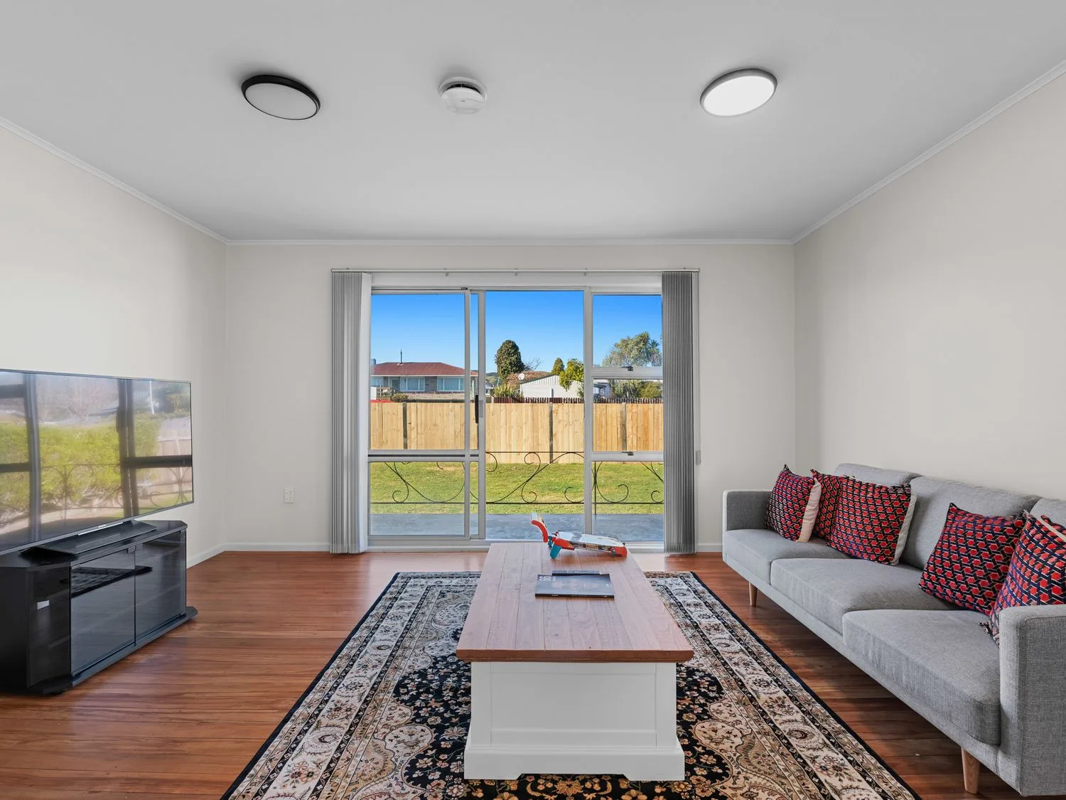 A living room with gray seating, patterned cushions, a coffee table, and a television.