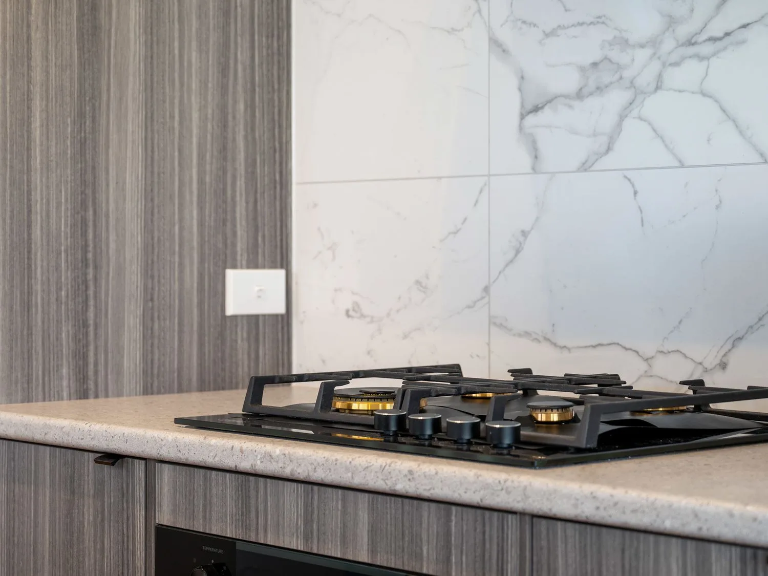 A kitchen countertop with a gas cooktop and a veined backsplash.