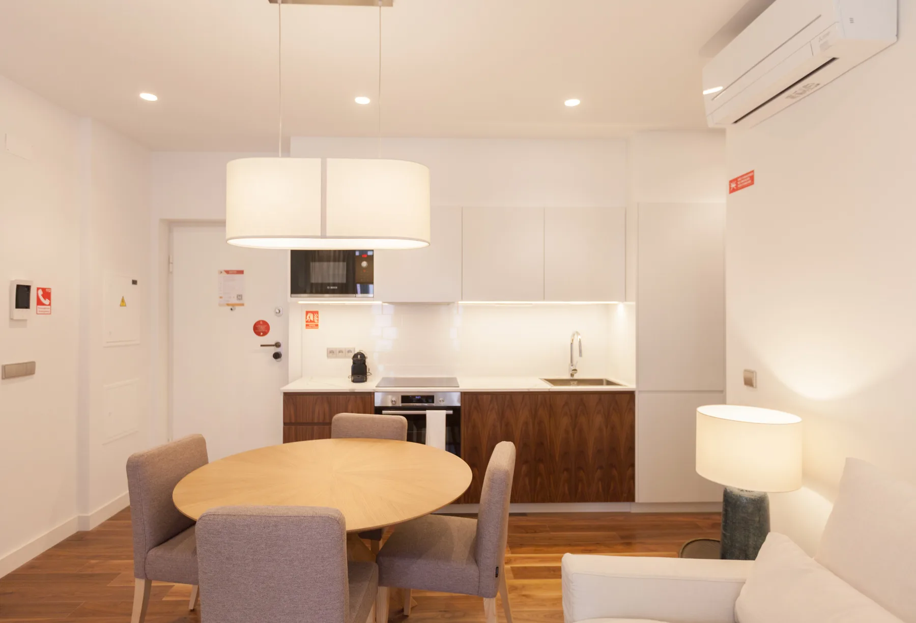 A dining area with a round table sits beside a compact kitchen.