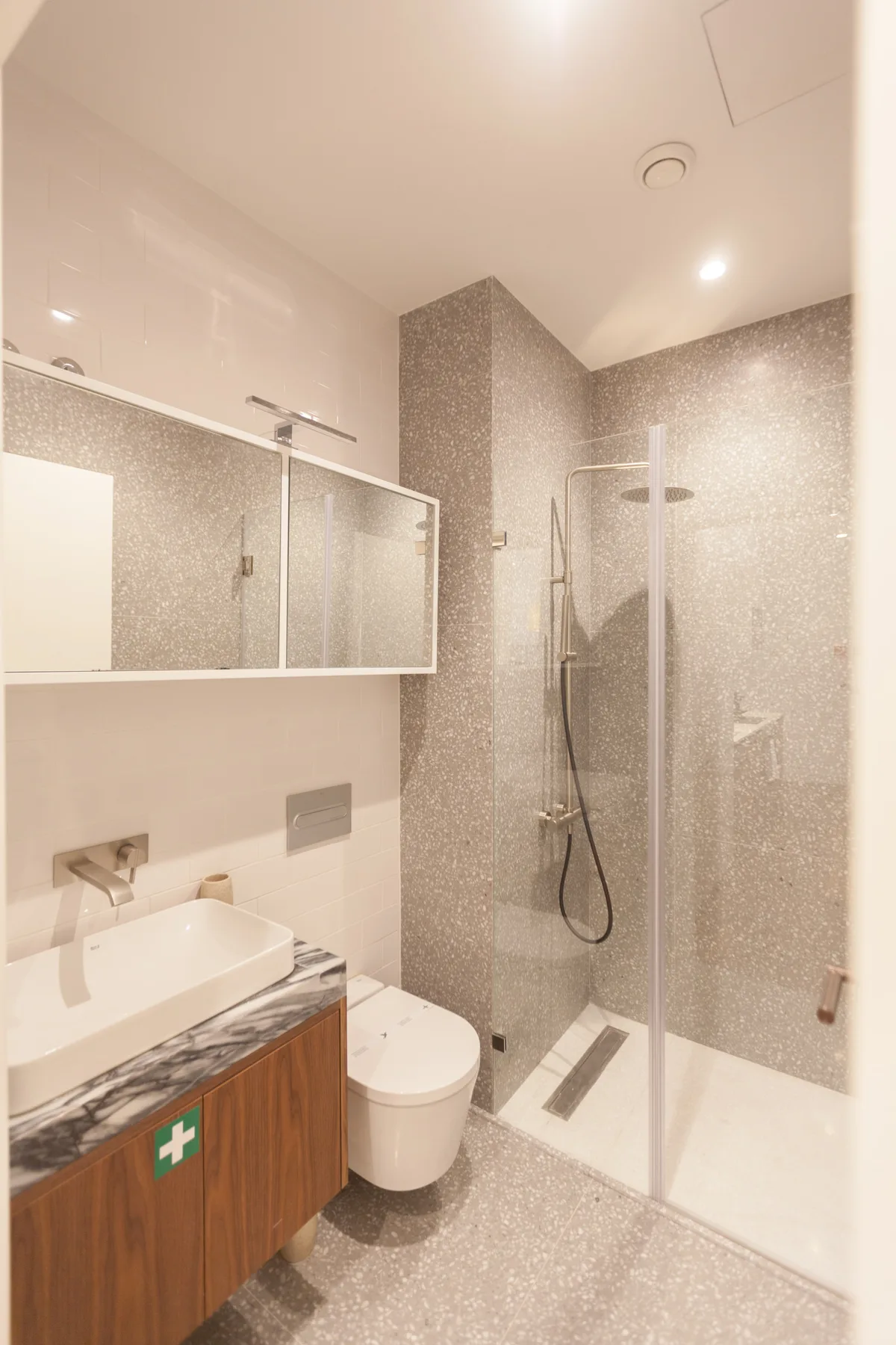 A modern bathroom with a vanity, toilet, and glass-enclosed shower.