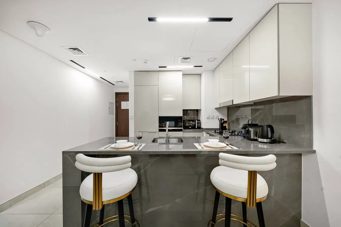 Una cocina moderna y luminosa con una isla central y dos taburetes.