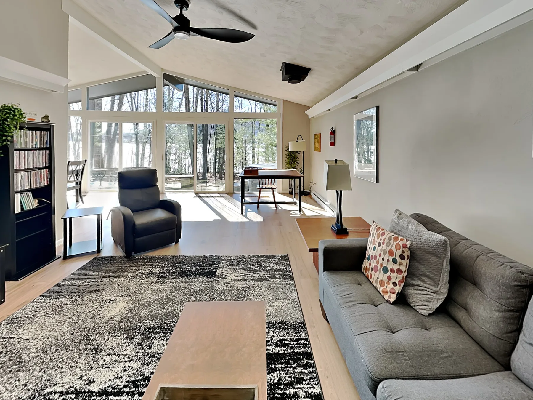 A bright living room with seating, a rug, and large windows.