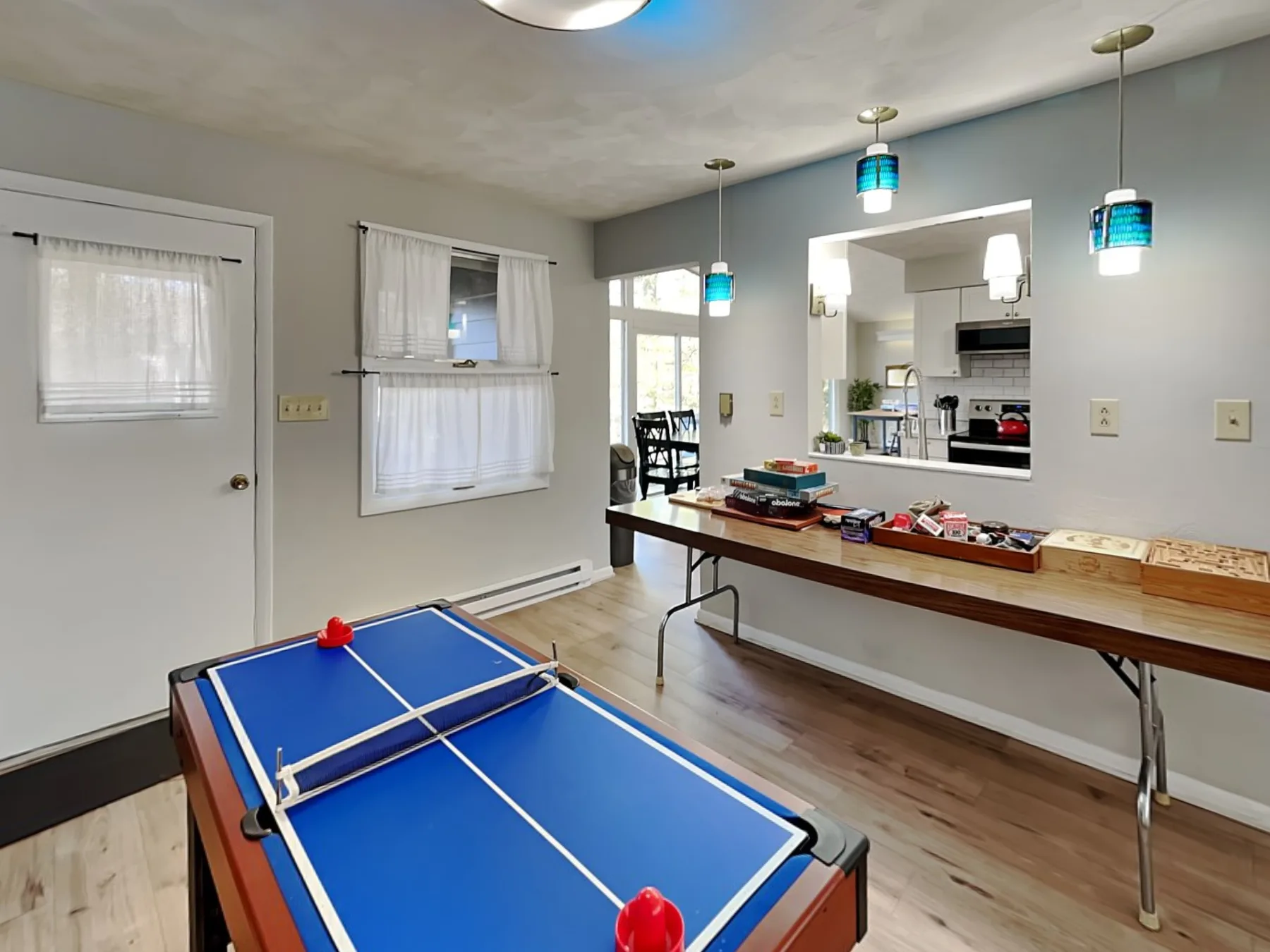 A recreation room has a blue ping-pong table beside a long counter.