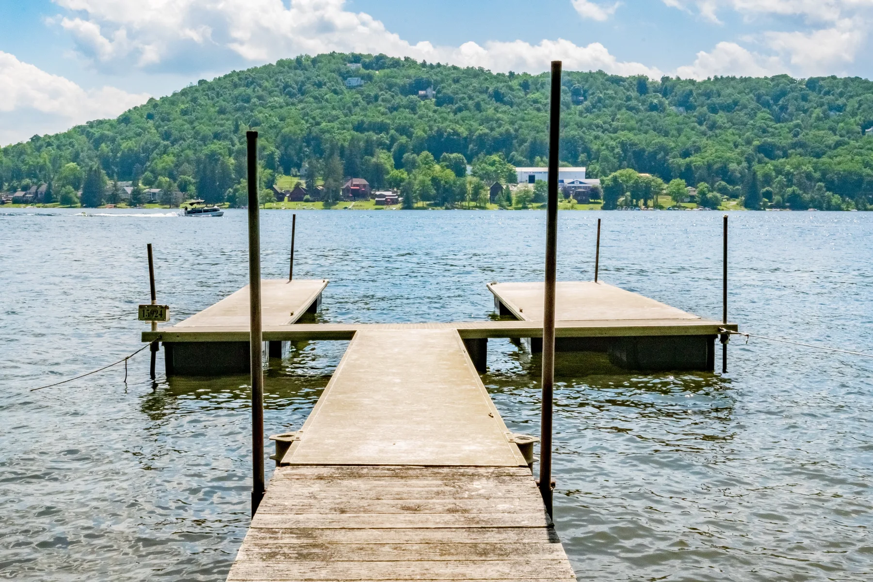 A wooden dock extends into a lake, with a wooded hillside across the water.