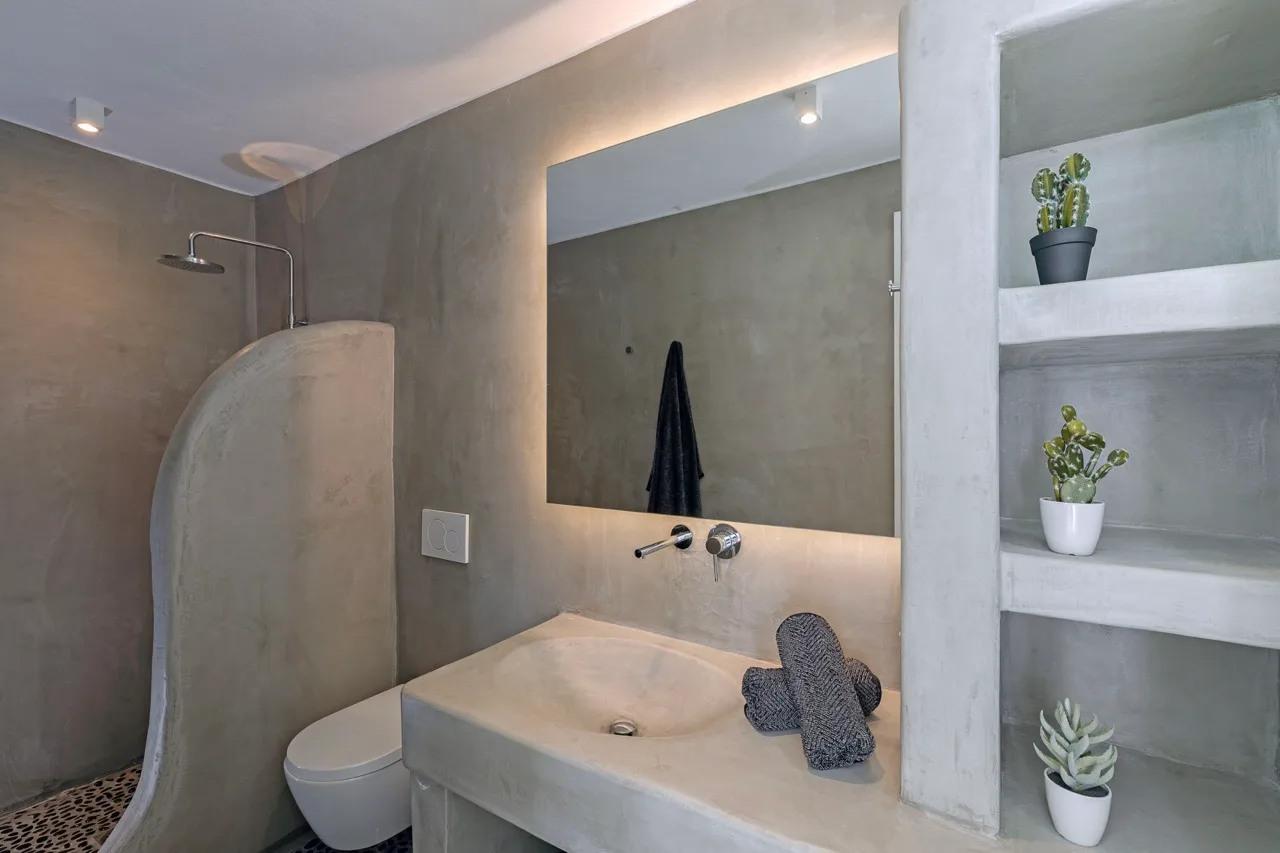 A bathroom with a sink, mirror, and shower.