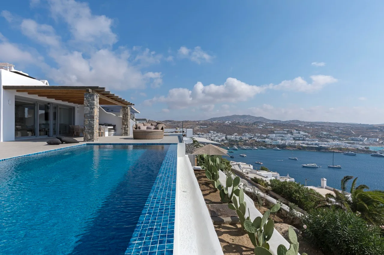 A poolside terrace overlooks a bay and the surrounding coastline.