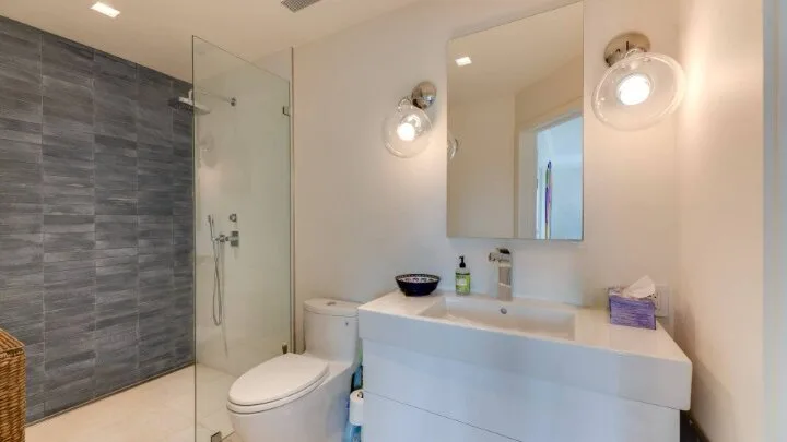 Un baño luminoso con ducha de vidrio, inodoro y lavabo con mueble.