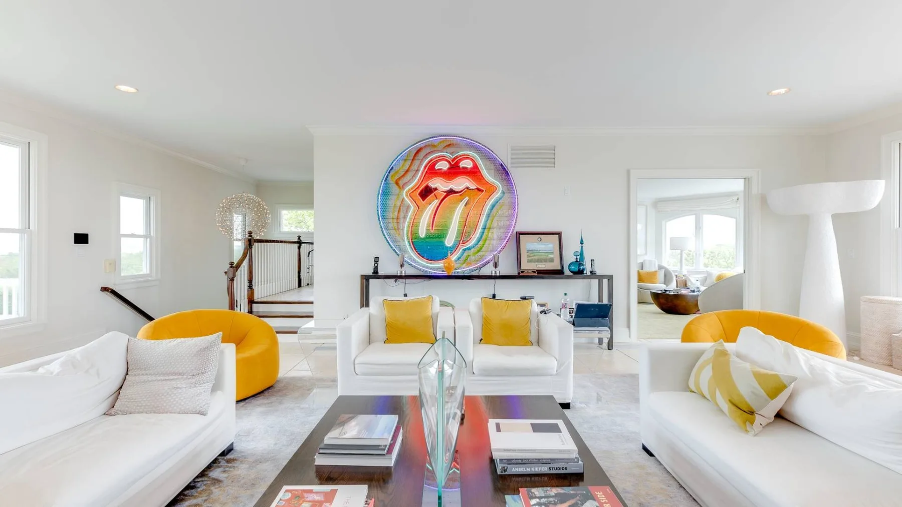 Una sala luminosa con asientos blancos y una obra colorida sobre la chimenea.