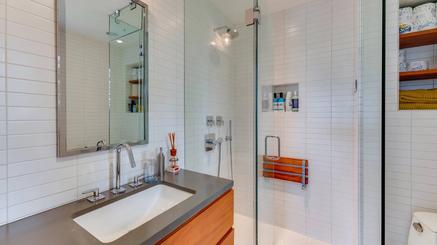 Un baño revestido de azulejos con lavabo y ducha de vidrio.