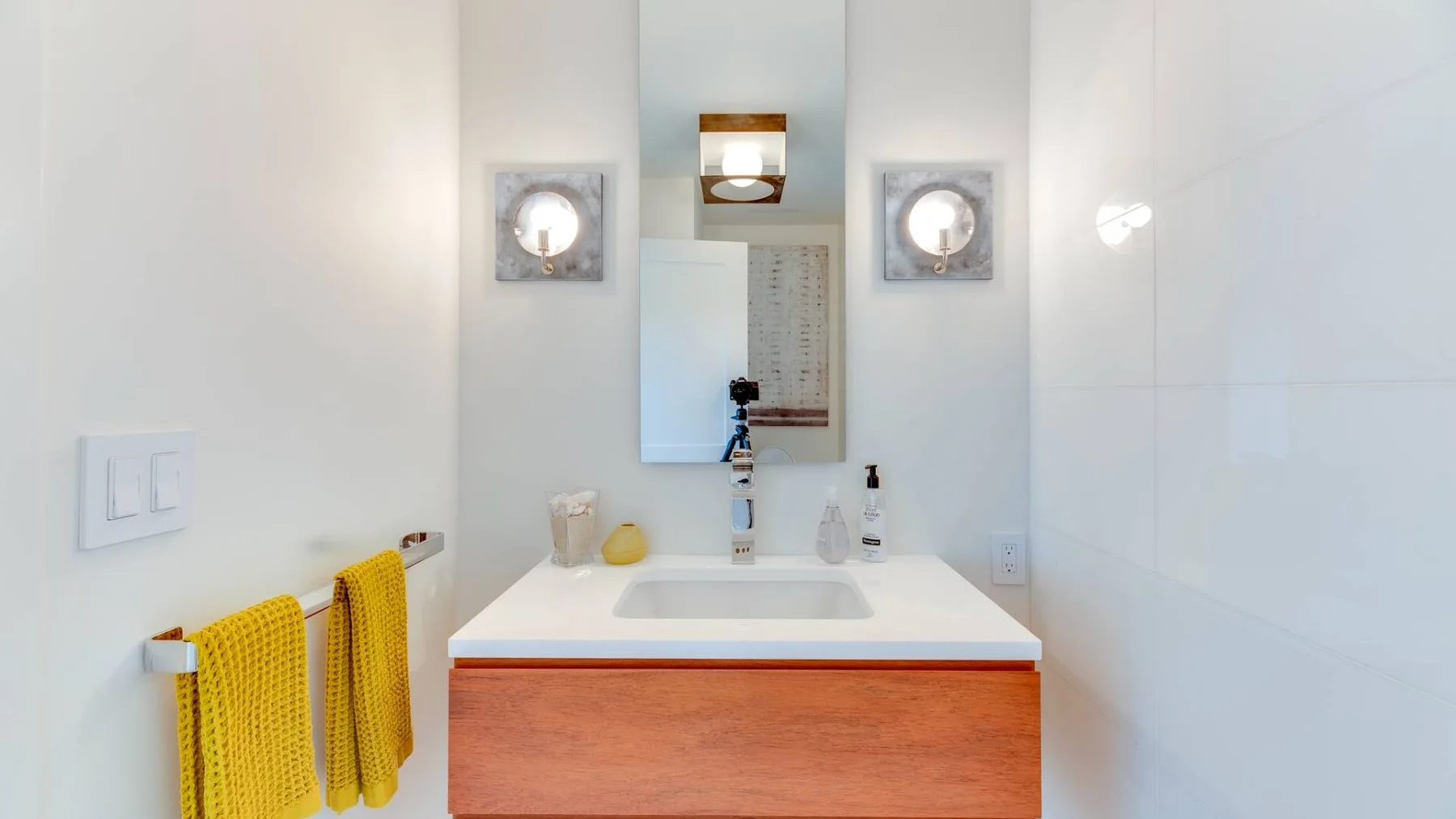 Un lavabo de baño con espejo y toallas amarillas.