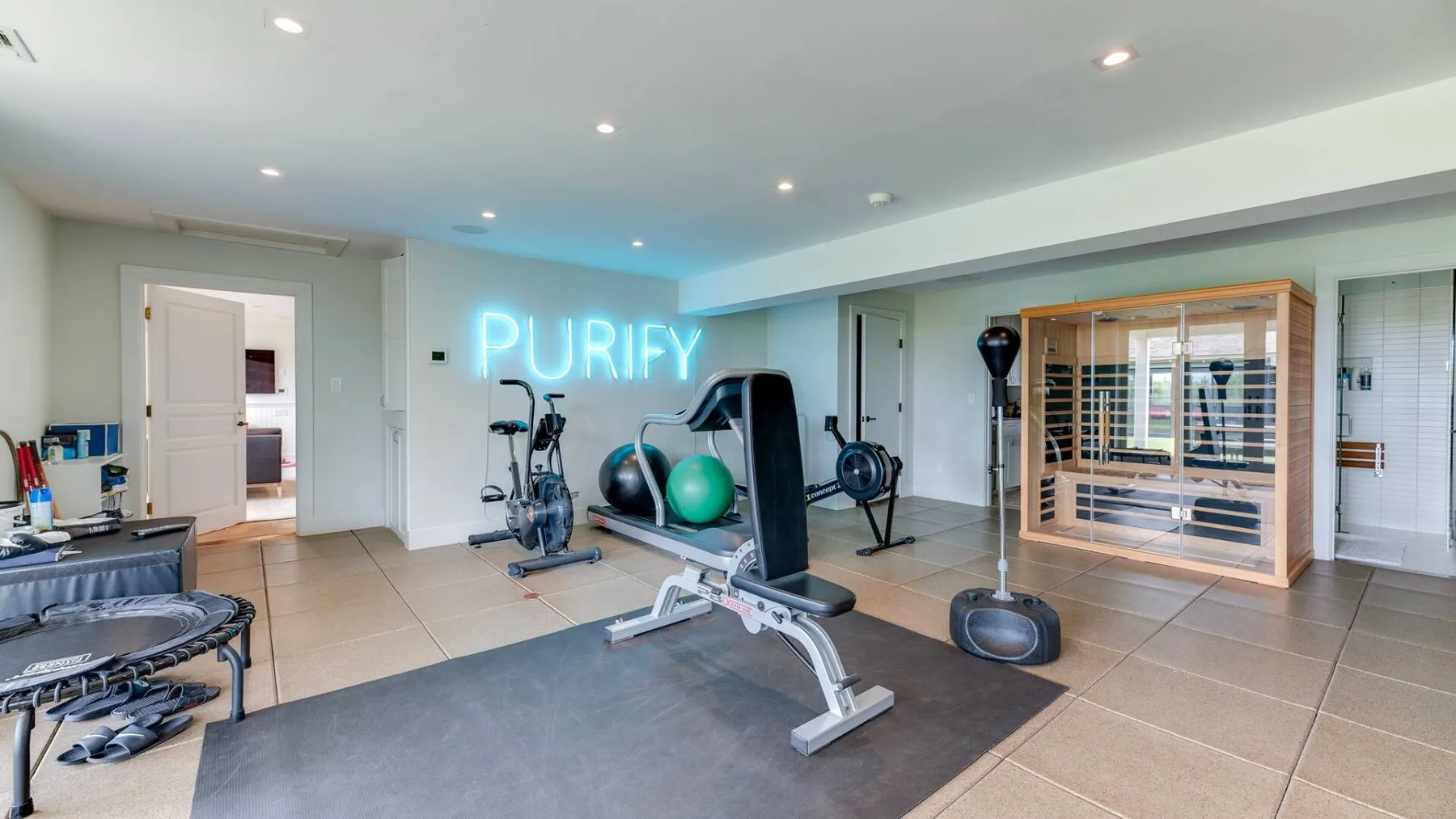 Una sala de ejercicios luminosa con equipos de entrenamiento y una sauna de madera.