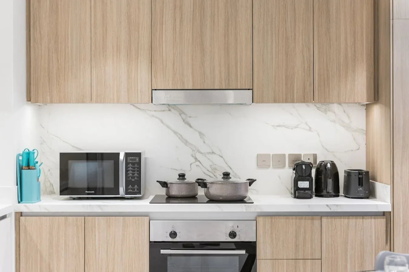 Una cocina moderna con armarios de madera, un salpicadero veteado y electrodomésticos sobre la encimera.