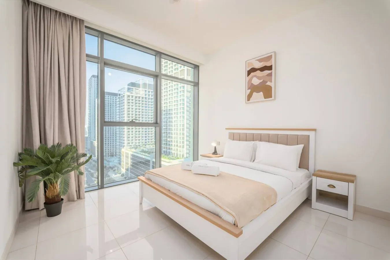 Un dormitorio luminoso con una cama tendida junto a una ventana grande.