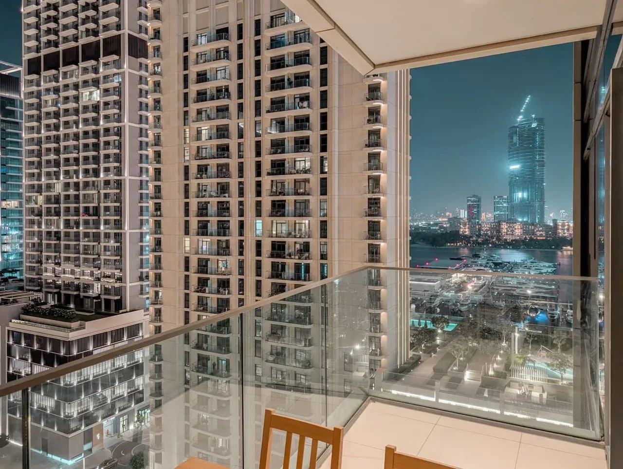Un balcón tiene vistas a edificios altos iluminados y al horizonte de la ciudad por la noche.