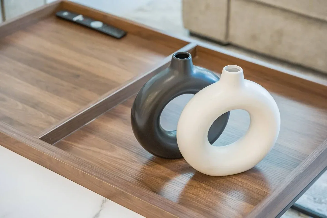 Dos jarrones decorativos están sobre una bandeja de madera en una mesa.