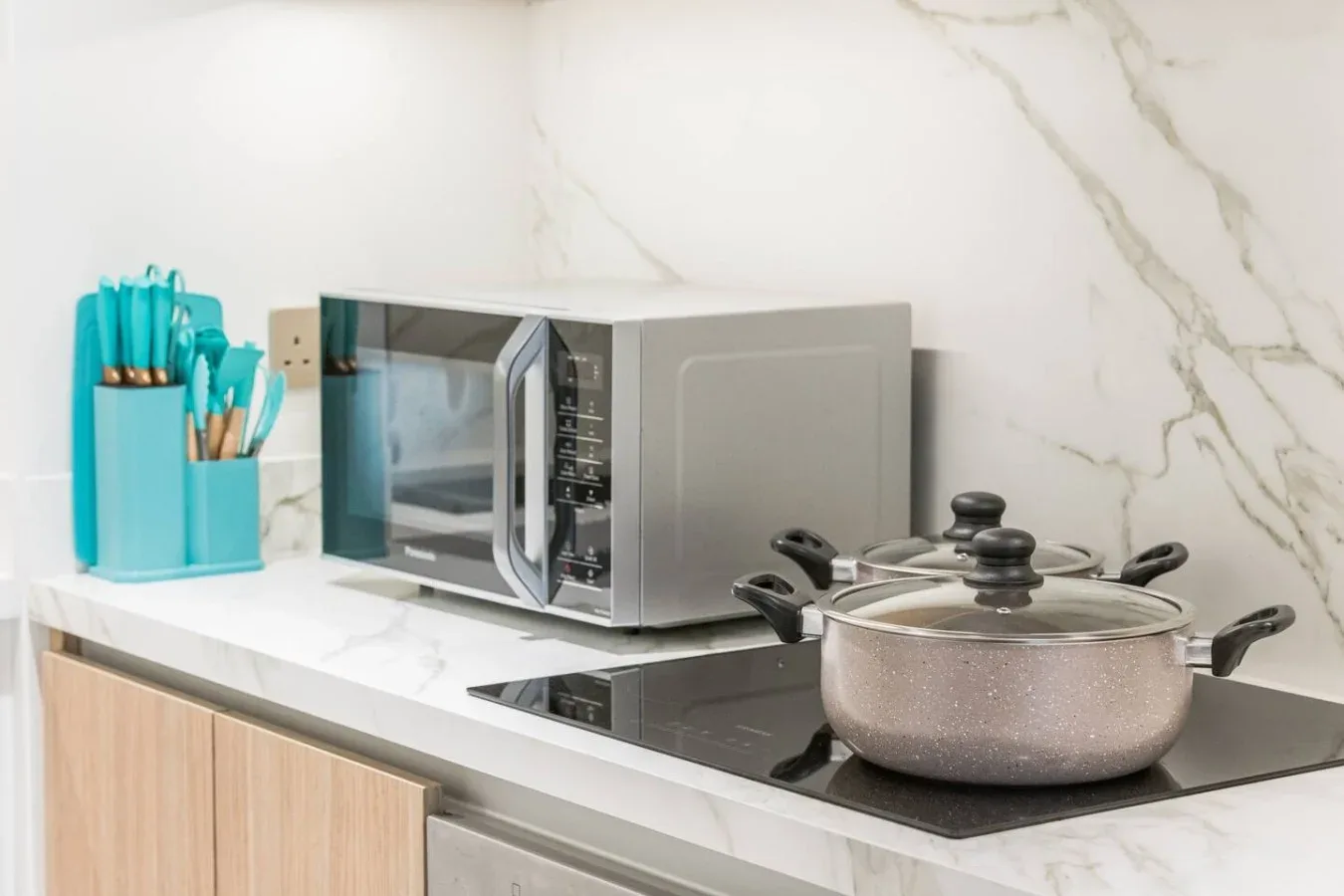 Una encimera de cocina con microondas, placa de cocción y olla.