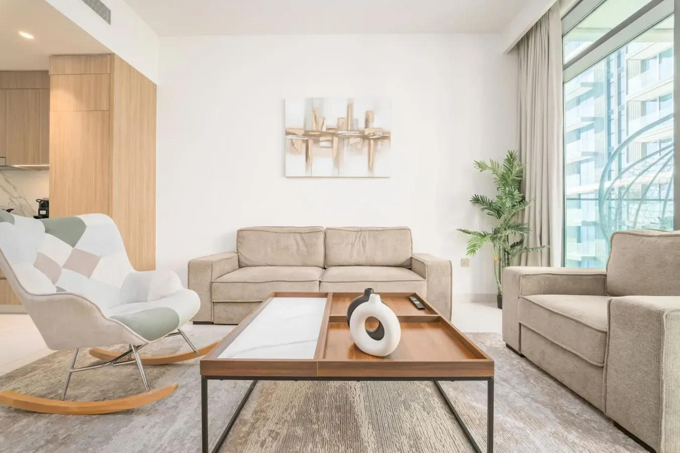 Una sala luminosa con asientos alrededor de una mesa de centro junto a grandes ventanas.