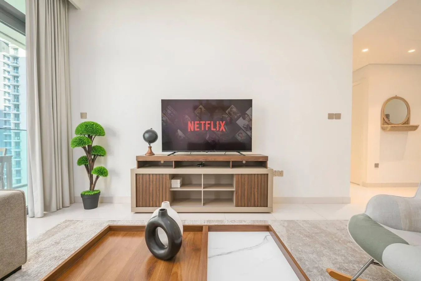 Una sala luminosa con un televisor sobre un mueble bajo y asientos.