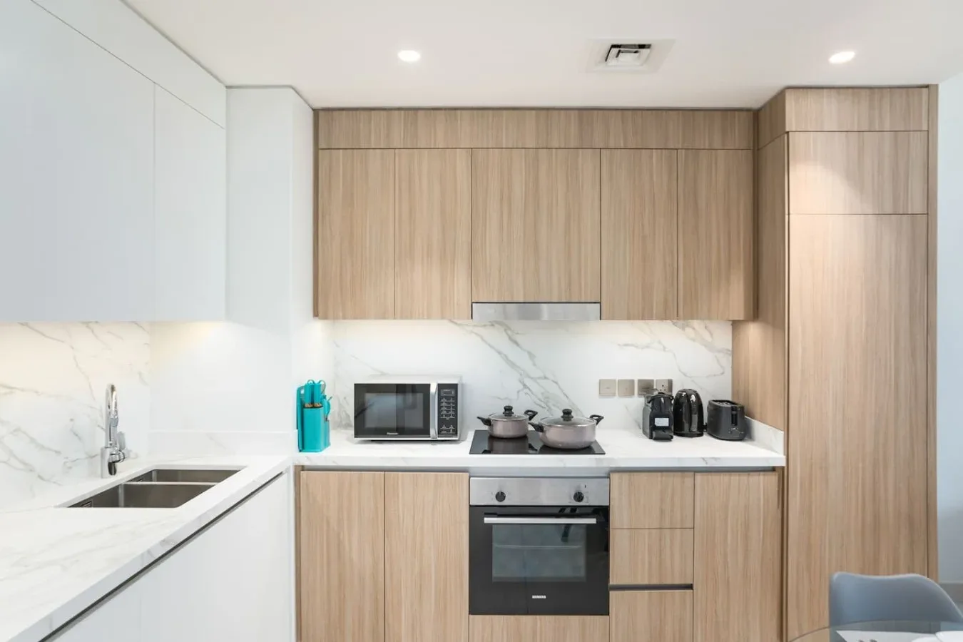 Una cocina moderna con gabinetes de madera clara, una encimera y electrodomésticos integrados.