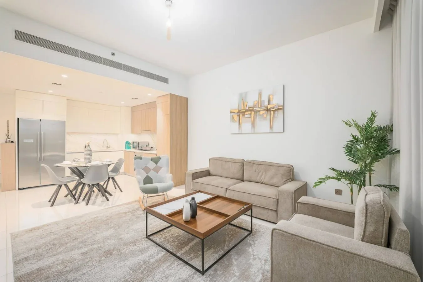 Una luminosa sala de estar y comedor de planta abierta con un sofá beige y una mesa.